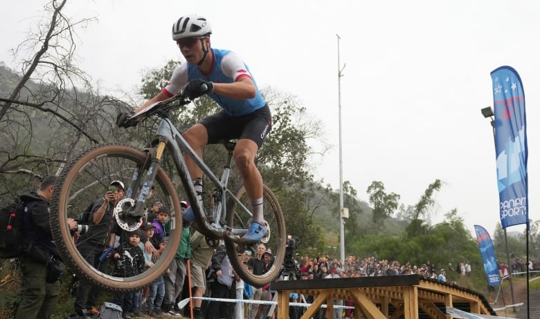 A man rides a mountain bike off a ramp.