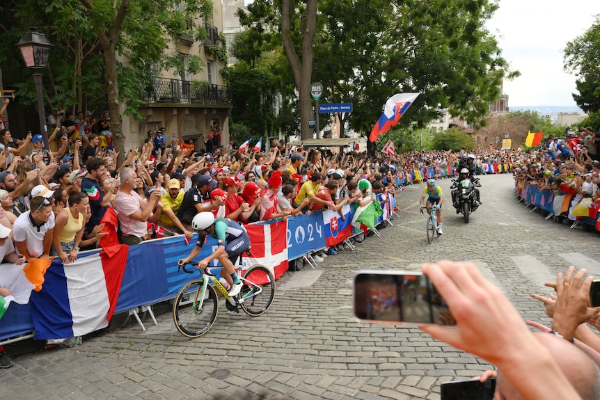 Ben Healy rides with crowd members taking photos