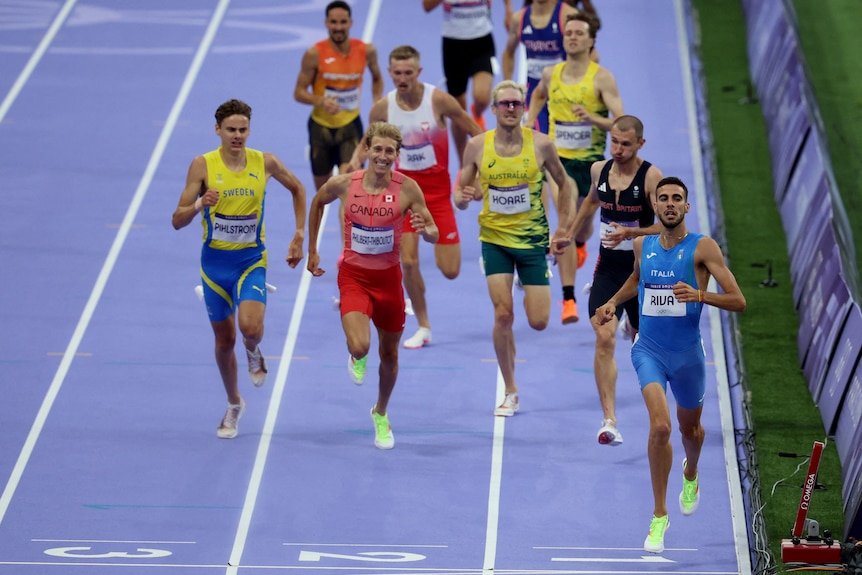 Male sprinters run towards the camera.