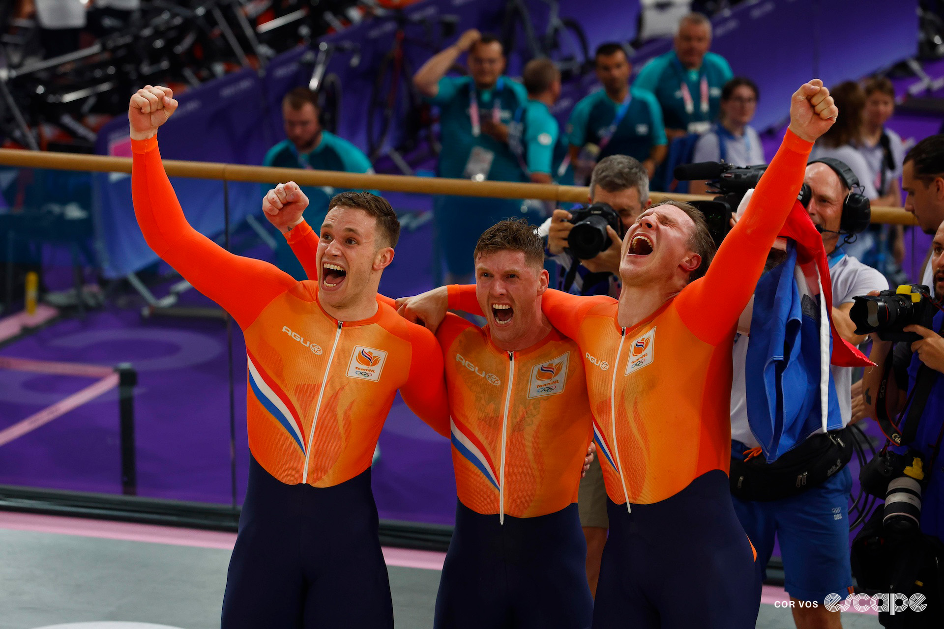 Harrie Lavreysen, Roy van den Berg and Jeffrey Hoogland of the Netherlands stand together trackside, punching the air in celebration of their Olympic gold medal in the team sprint in Paris 2024.