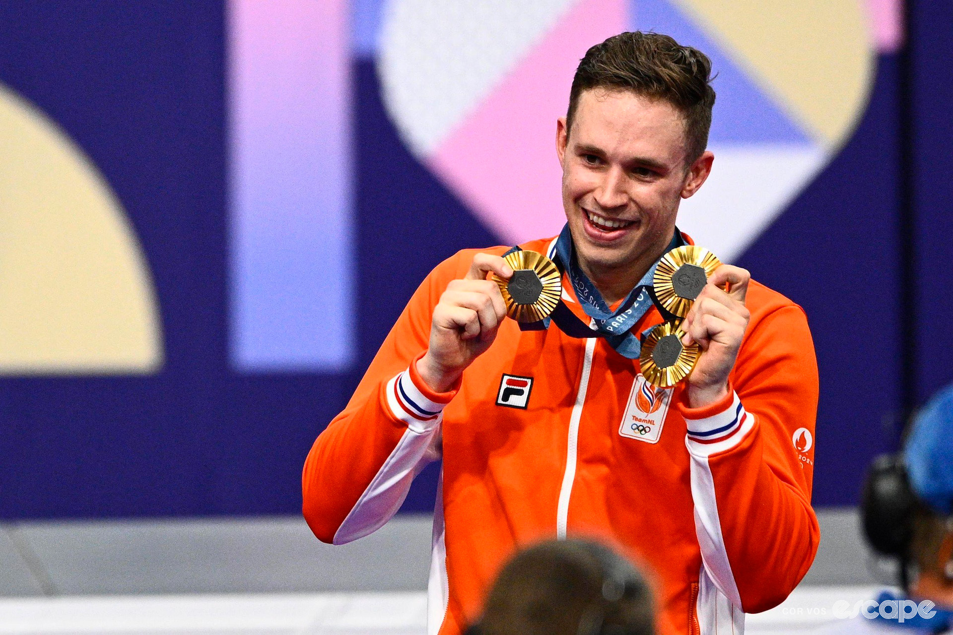 Harrie Lavreysen on the podium showing off his three gold medals at the 2024 Paris Olympics.