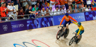 Harrie Lavreysen and Matthew Richardson pat one another on the back after their sprint final at the 2024 Paris Olympics, the Olympic rings emblazoned on the steep boards of the track just in front of them.