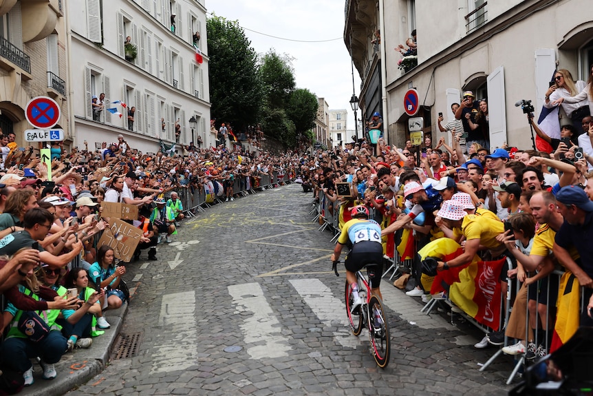 Remco Evenepoel climbs a hill with crowds lining the road