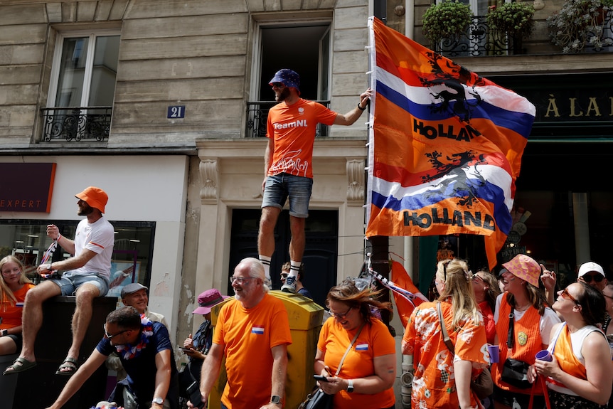 A Dutch fan wearing orange stands above the crowd