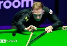 Judd Trump plays a shot, using the rest