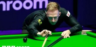 Judd Trump plays a shot, using the rest