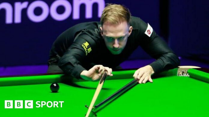 Judd Trump plays a shot, using the rest