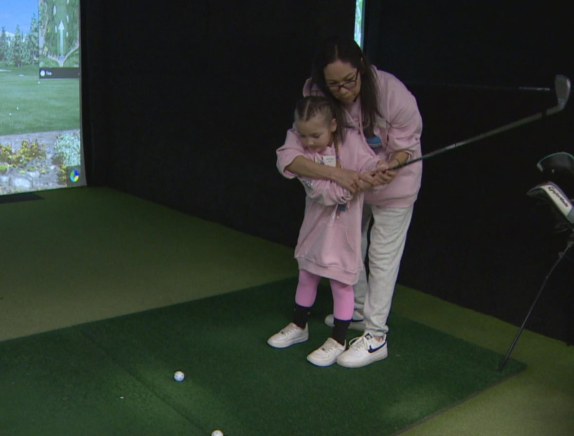 An instructor helps a small girl with her swing.