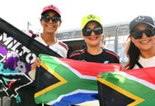 Three Formula 1 fans wear Mercedes branded caps and hold up South African flags and a banner reading 'Hamilton 44'