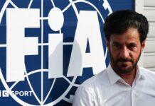 Mohammed Ben Sulayem stands in front of an FIA sign 