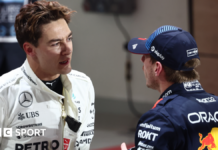 George Russell and Max Verstappen talk to each other in the pit lane