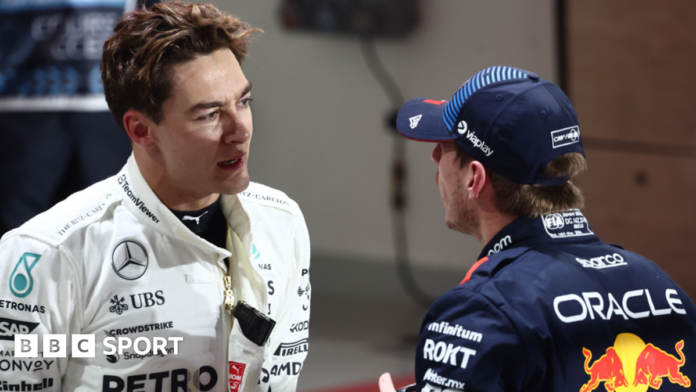 George Russell and Max Verstappen talk to each other in the pit lane