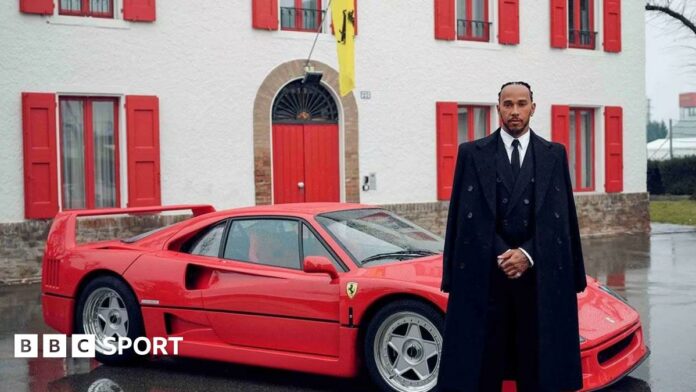 Lewis Hamilton stood alongside a Ferrari sports car while wearing a black suit and black overcoat