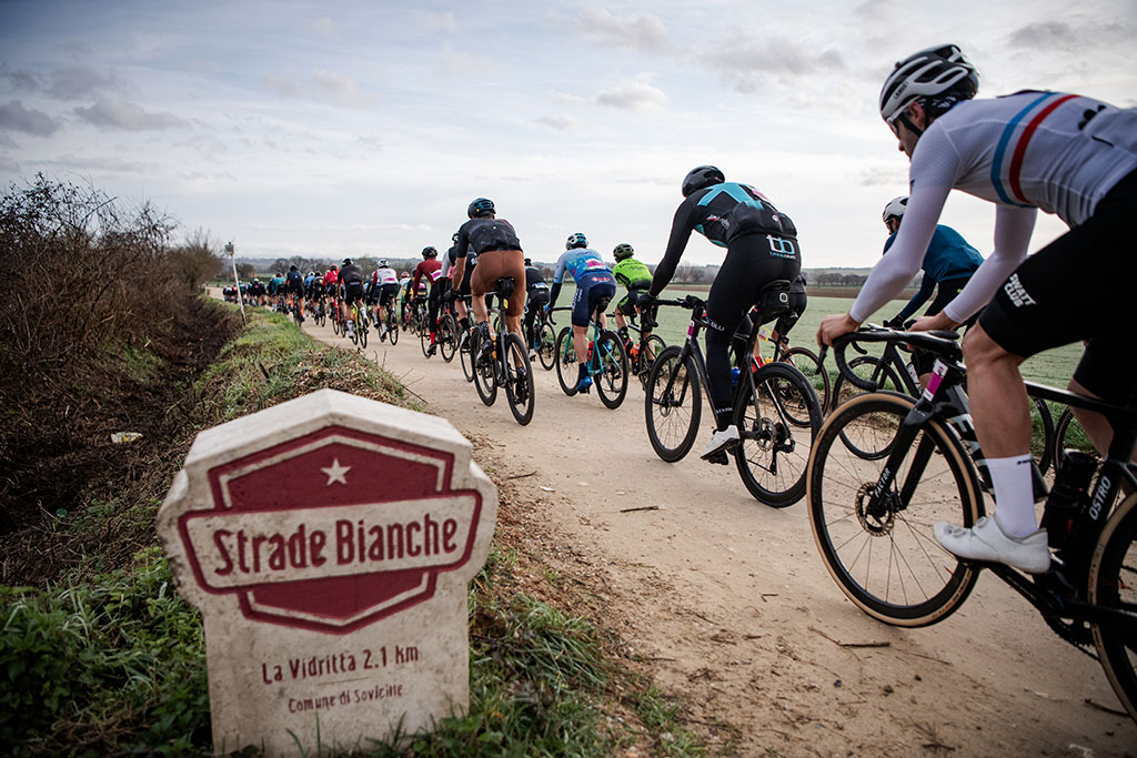 Cyclists ride the white gravel roads of Tuscany on the Gran Fondo Strade Bianche