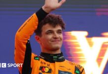 Lando Norris waves on the podium as he celebrates winning the Australian Grand Prix