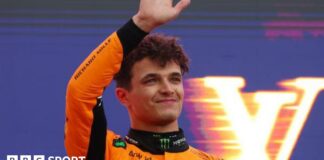 Lando Norris waves on the podium as he celebrates winning the Australian Grand Prix