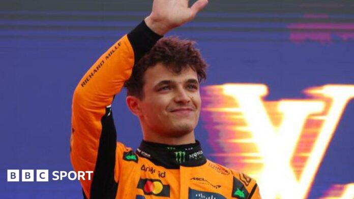 Lando Norris waves on the podium as he celebrates winning the Australian Grand Prix