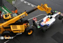 A crane lifting up Isack Hadjar's Racing Bulls car