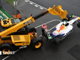 A crane lifting up Isack Hadjar's Racing Bulls car