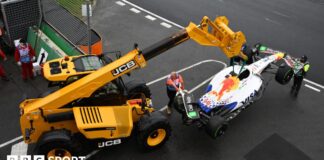 A crane lifting up Isack Hadjar's Racing Bulls car