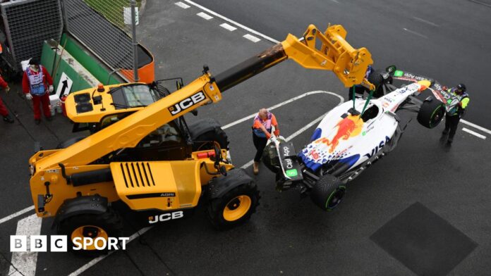 A crane lifting up Isack Hadjar's Racing Bulls car