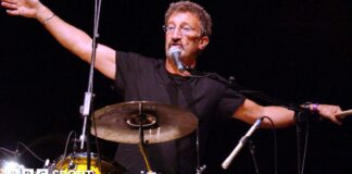 Eddie Jordan with his arms outstretched while playing the drums