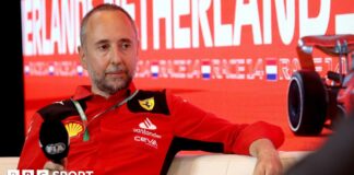 Enrico Cardile wearing a Ferrari top and holding an FIA-branded microphone