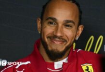 Lewis Hamilton smiling while wearing a Ferrari jacket during the drivers' press conference before the Australian Grand Prix