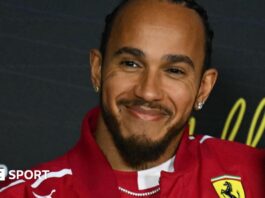 Lewis Hamilton smiling while wearing a Ferrari jacket during the drivers' press conference before the Australian Grand Prix