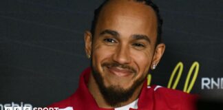 Lewis Hamilton smiling while wearing a Ferrari jacket during the drivers' press conference before the Australian Grand Prix